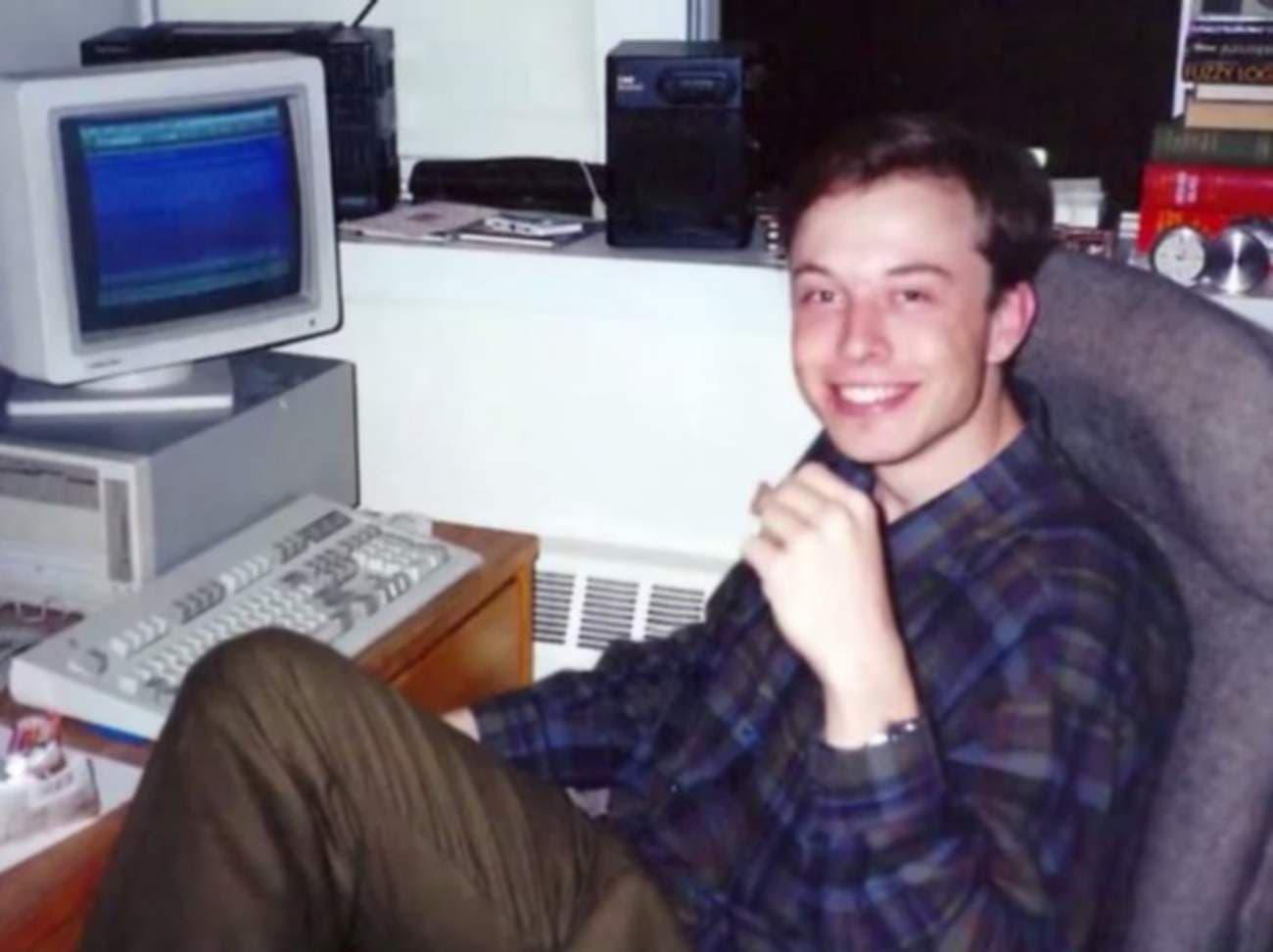 A young Elon Musk beside an early computer workstation